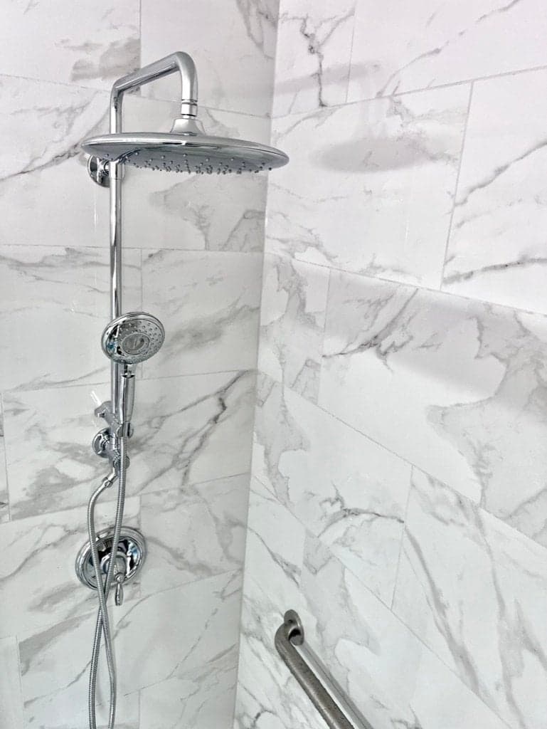 Chrome rain head shower with marble tile