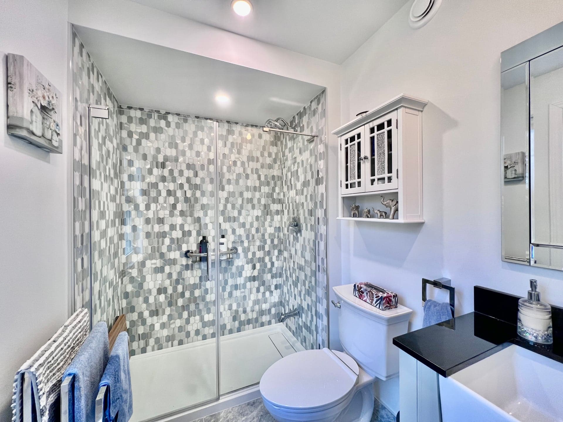 Standalone shower with sliding glass doors and mosaic tile surround