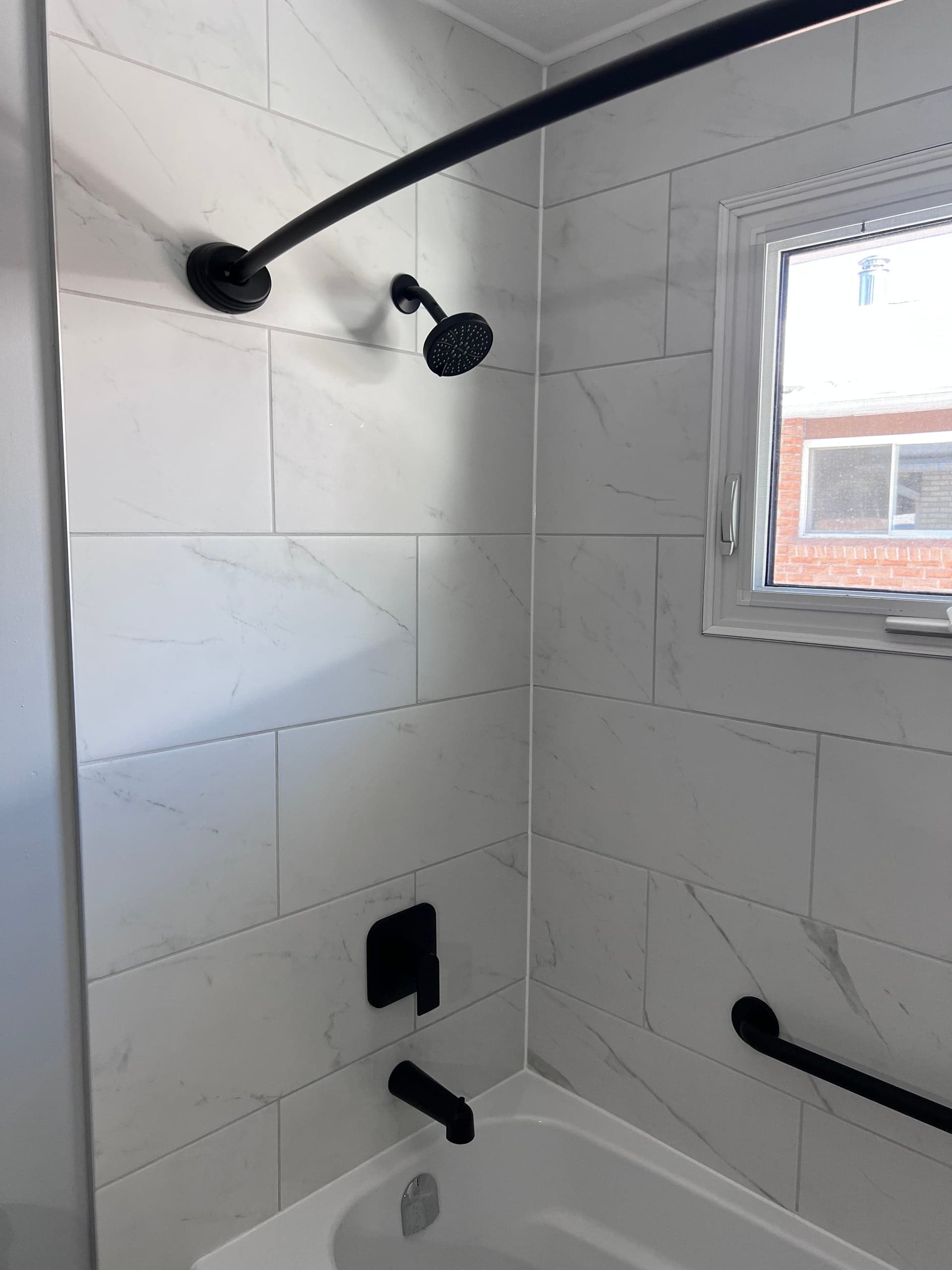 White marble tub and shower surround with black fixtures