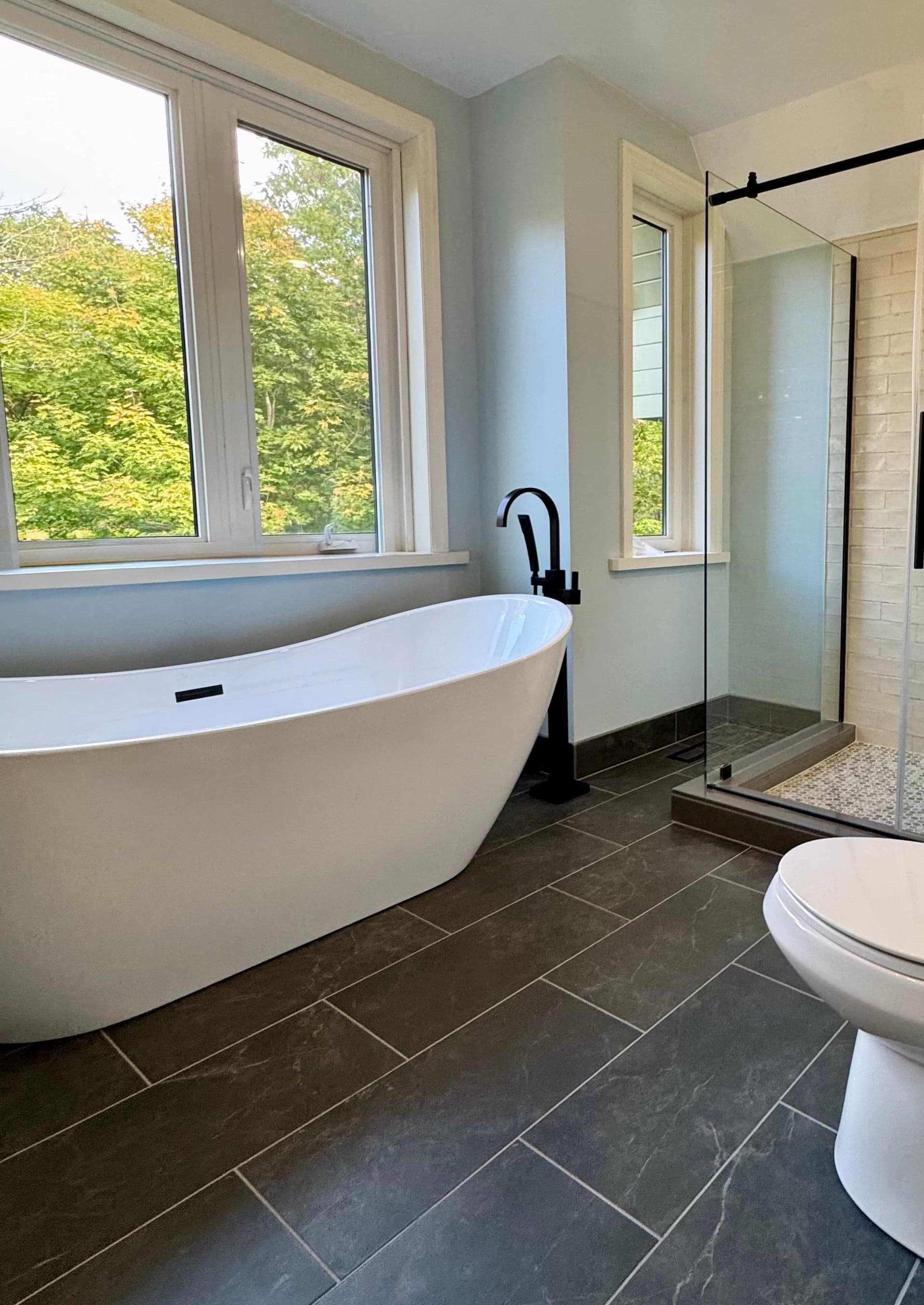 Brick-look tile shower with pebble mosaic floor and glass door